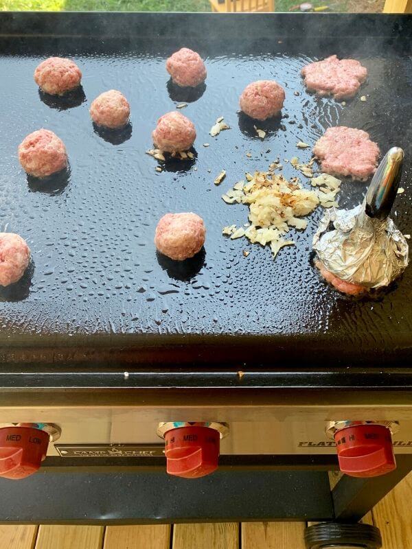 bacon cheeseburger sliders cooking on flat top griddle