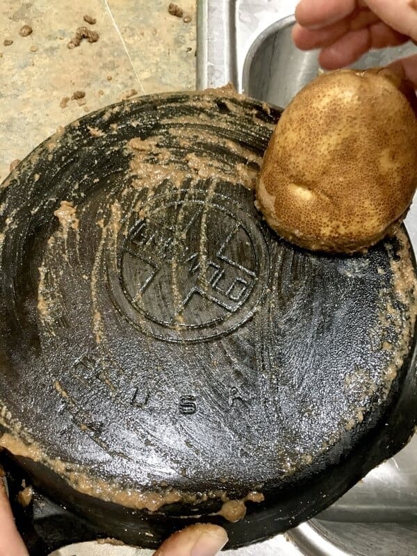 cut potato being rubbed on cast iron skillet