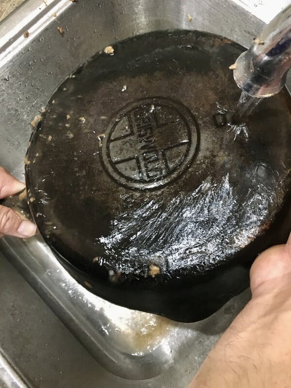 cast iron skillet being rinsed with water