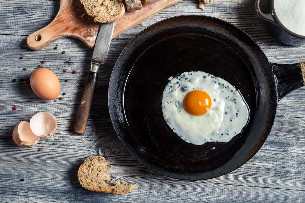 over easy egg cooking in a cast iron skillet