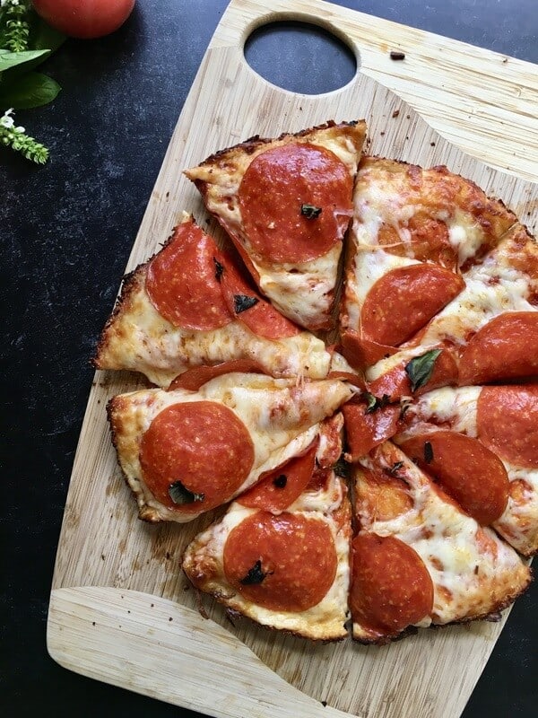 grilled cast iron pizza cut into slices on a cutting board