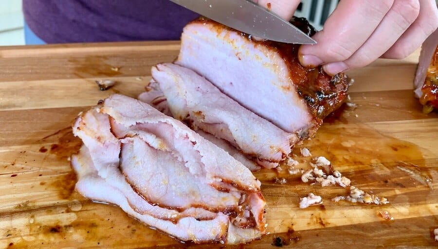 smoked pork loin being sliced on a cutting board
