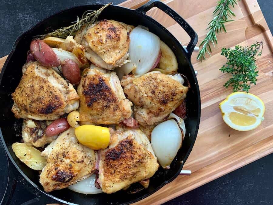 chicken thighs potatoes garlic onions and lemon in a cast iron skillet