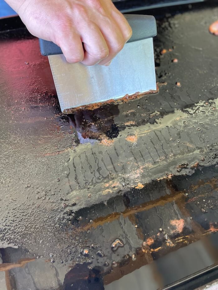 using a scraper to clean a griddle