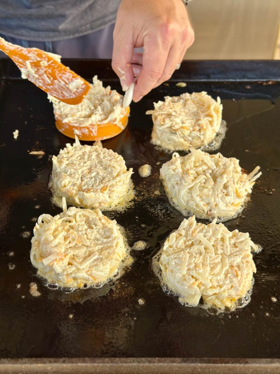 using an egg mold to portion hash brown casserole on a griddle