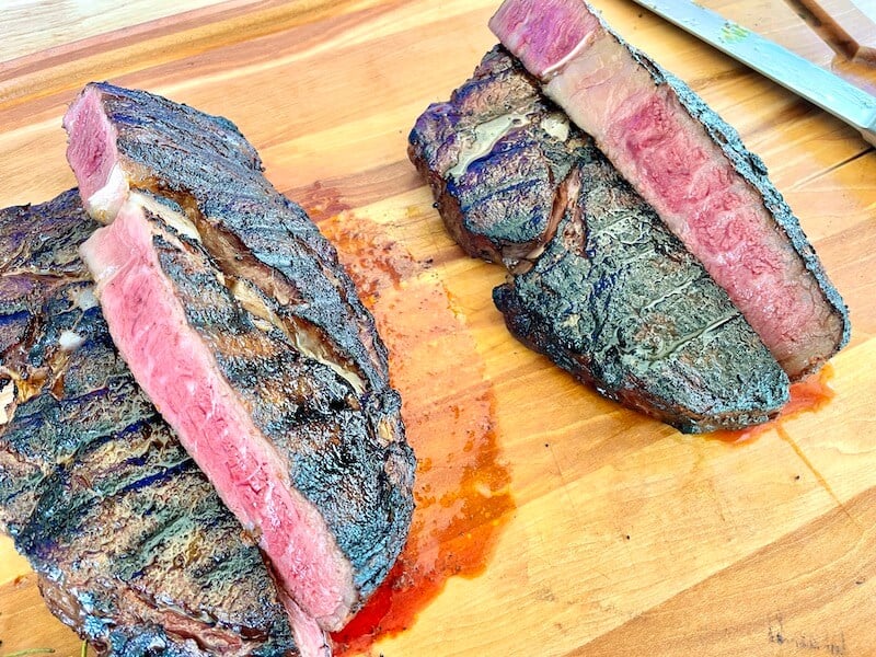 grilled ribeyes cut open on a cutting board