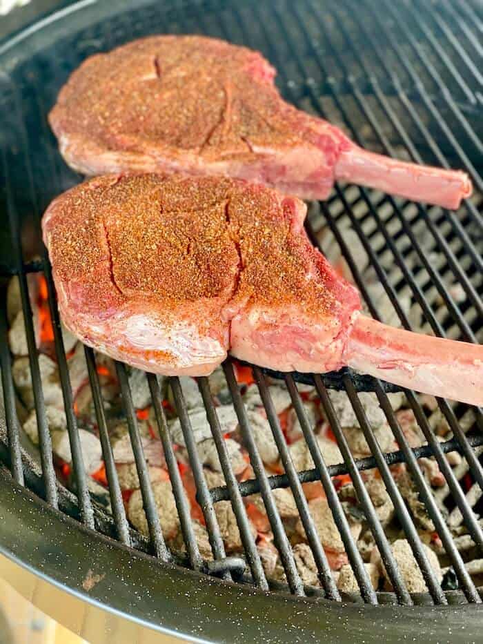 2 thick cut steaks searing on a charcoal grill