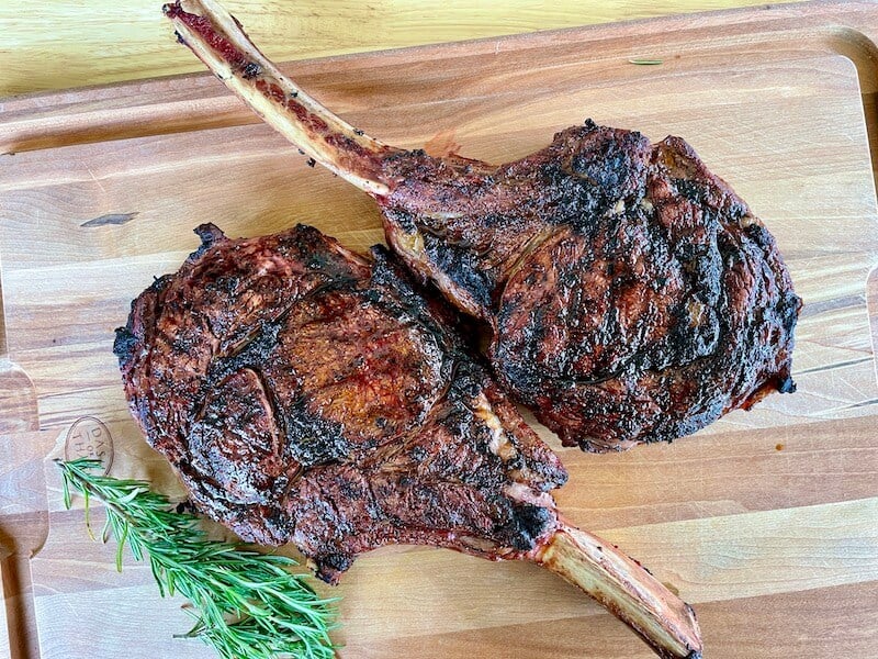 2 seared ribeye steaks resting on a cutting board