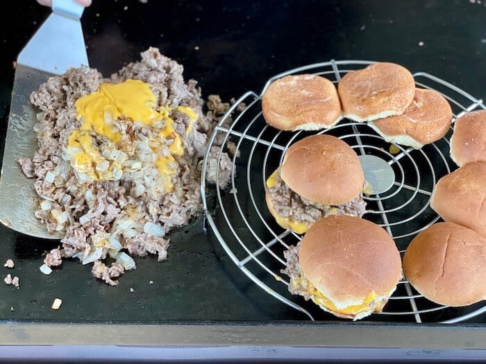 wire rack on an outdoor griddle with cheesesteak sandwiches on top
