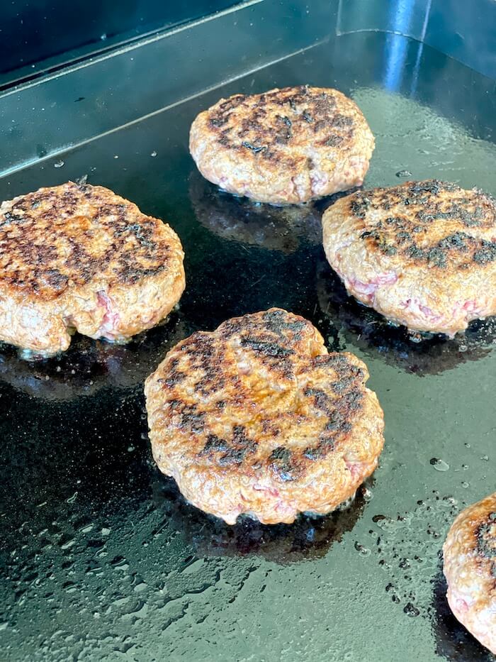 thick burger patty cooking on a flat top grill