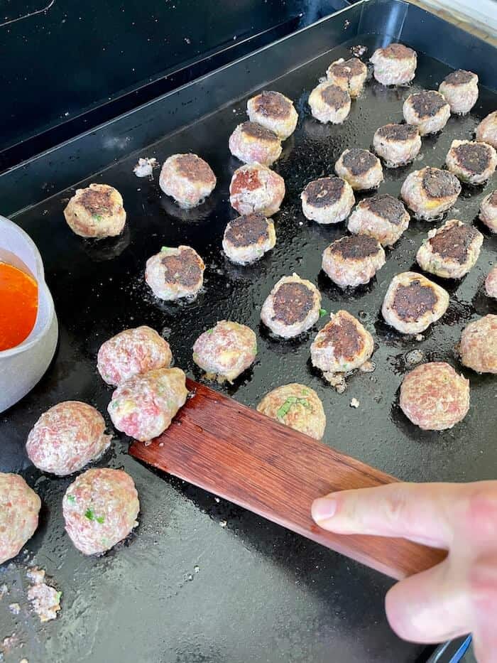 flipping homemade meatballs on the Pit Boss griddle