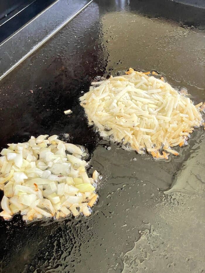 hash browns and onions cooking on a griddle