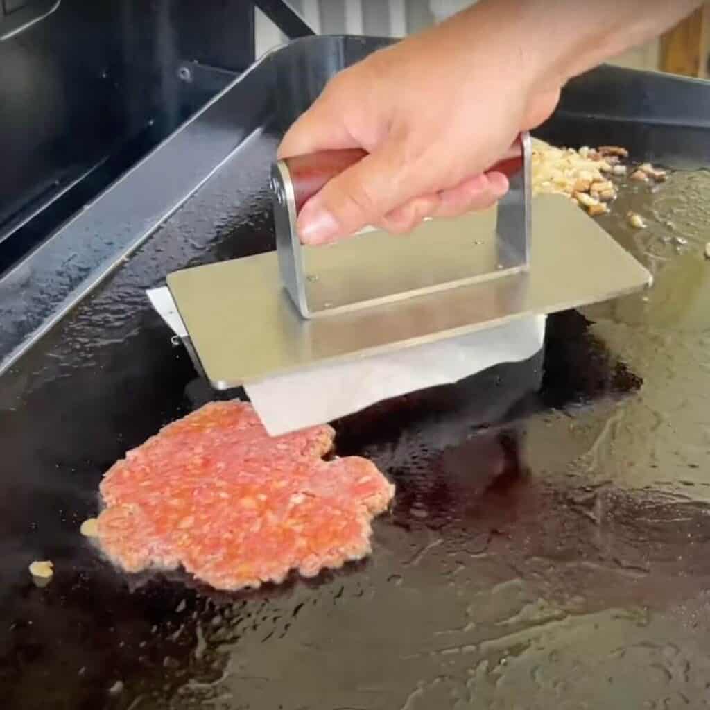 smashing down breakfast burger patties on the griddle