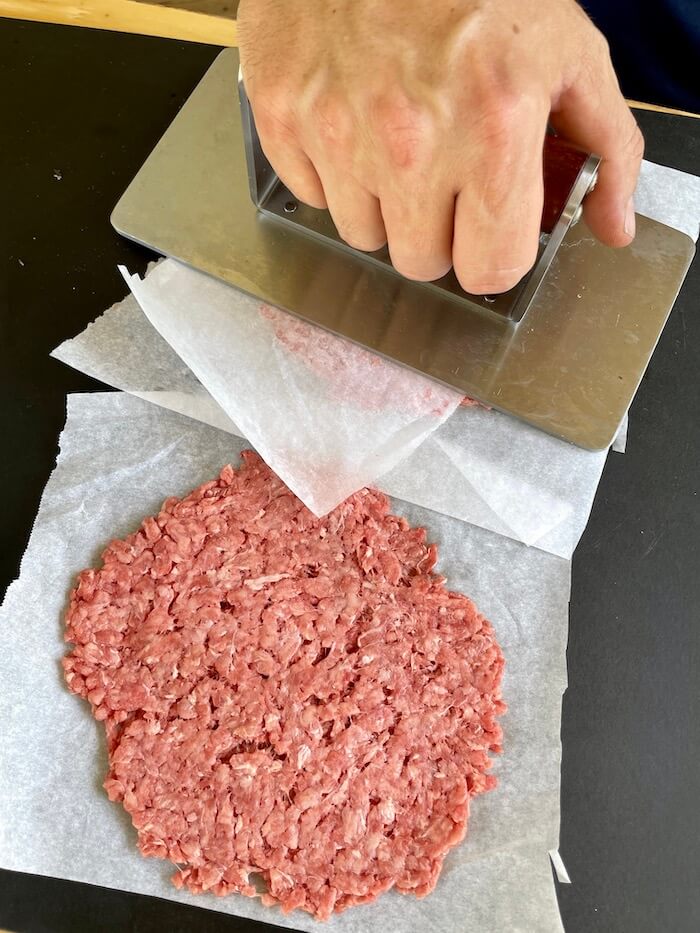 pressing down ground beef into thin patties