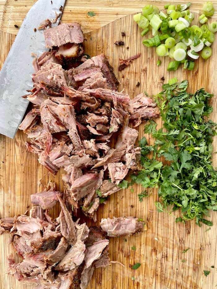 chopped brisket, green onion, and cilantro on a cutting board