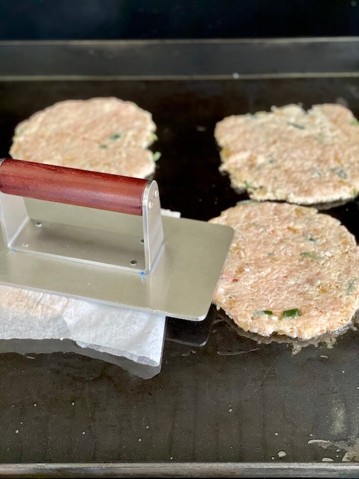 chicken smash burgers cooking on a griddle