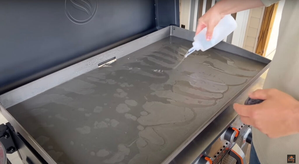 cleaning a Blackstone griddle with a squirt bottle of water