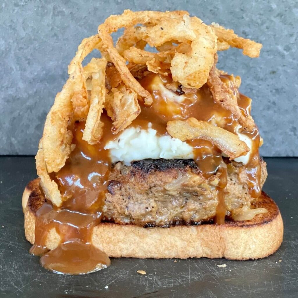 open faced meatloaf sandwich with mashed potatoes, gravy, and fried onions
