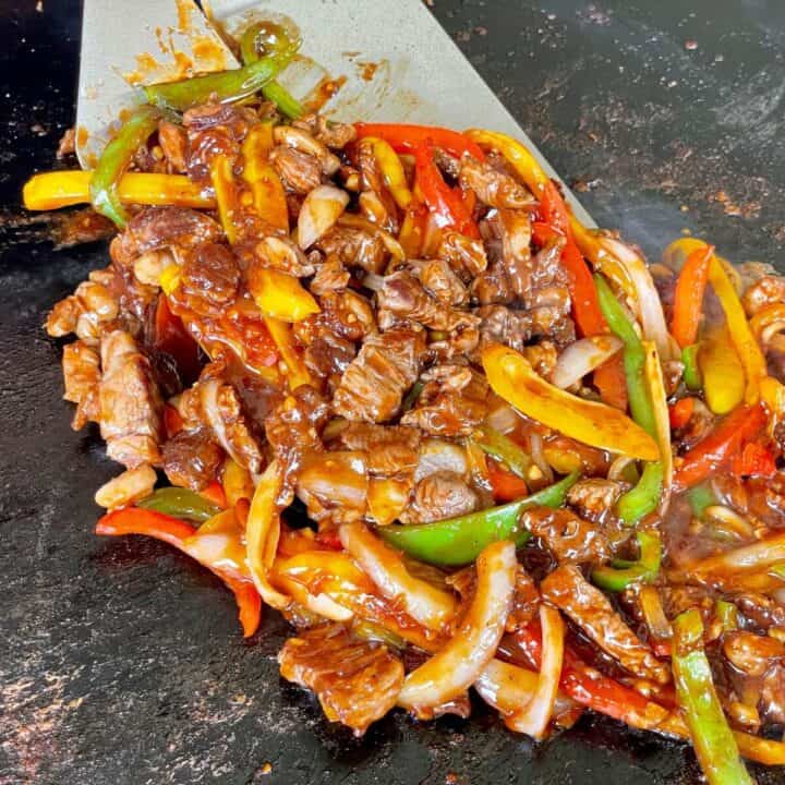 beef pepper steak being cooked on a Blackstone griddle