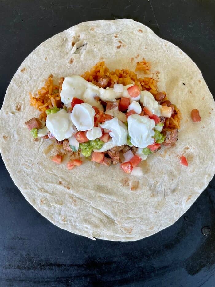 making a steak burrito on a flour tortilla