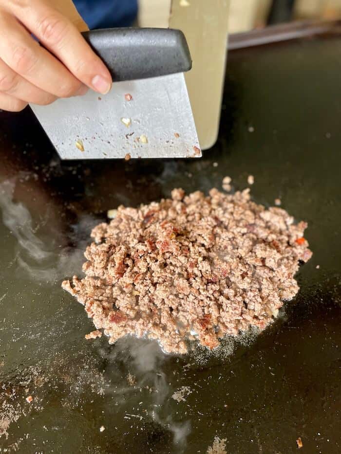 using a bench scraper to chop meat