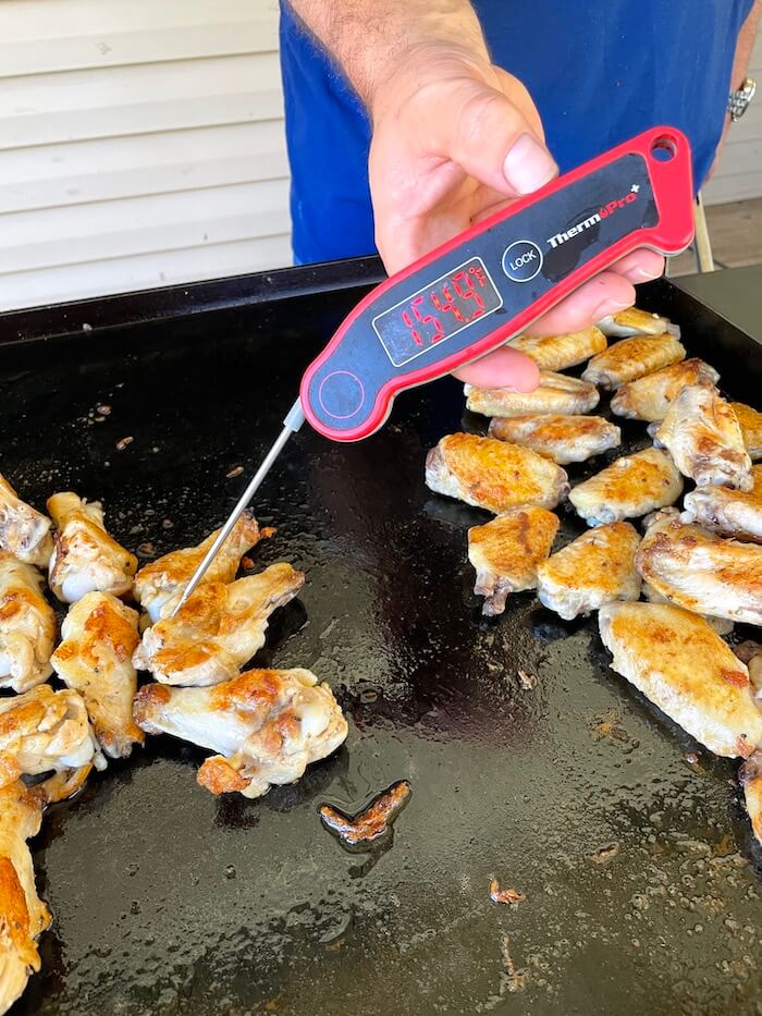 checking temperature of chicken wings on the Blackstone griddle