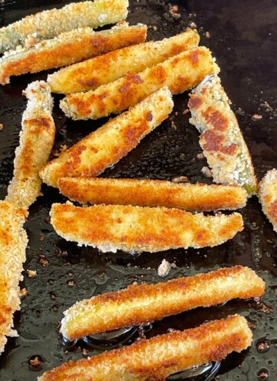 fried pickle spears cooking on a griddle