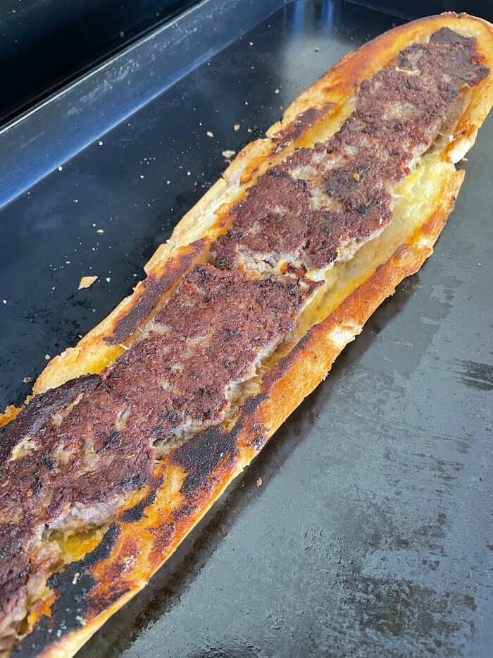Italian sausage stuffed bread cooking on a griddle