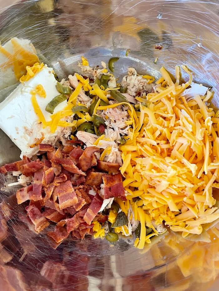 cream cheese, cheddar cheese, bacon, jalapenos, and chicken in a mixing bowl