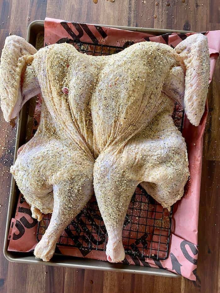 seasoned cider brined turkey on a wire rack and sheet pan