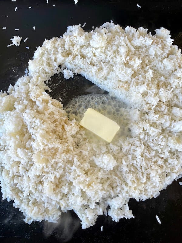 white rice and butter cooking on a blackstone griddle