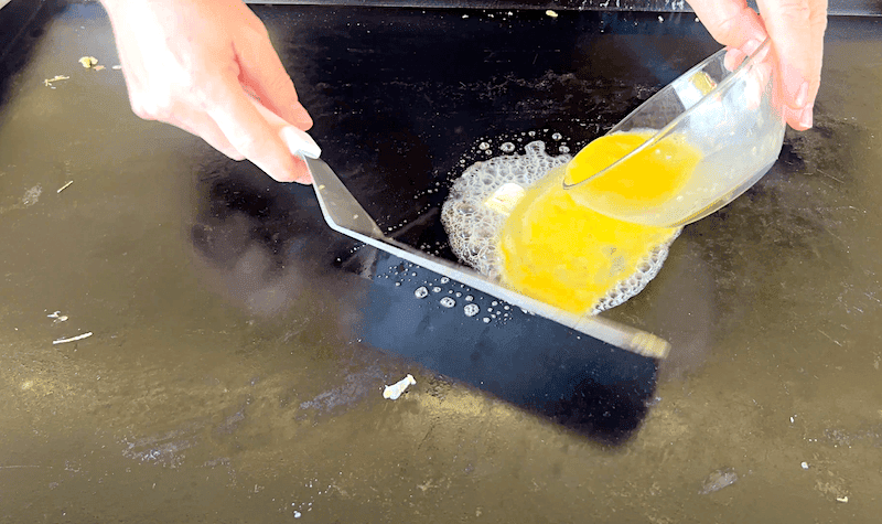 pouring scrambled eggs onto a blackstone griddle