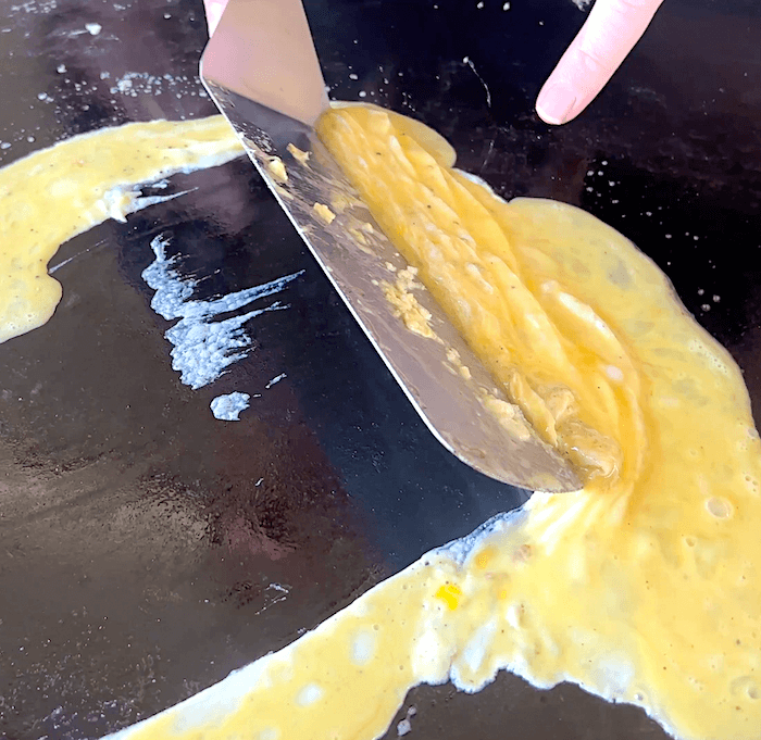 cooking scrambled eggs on a griddle