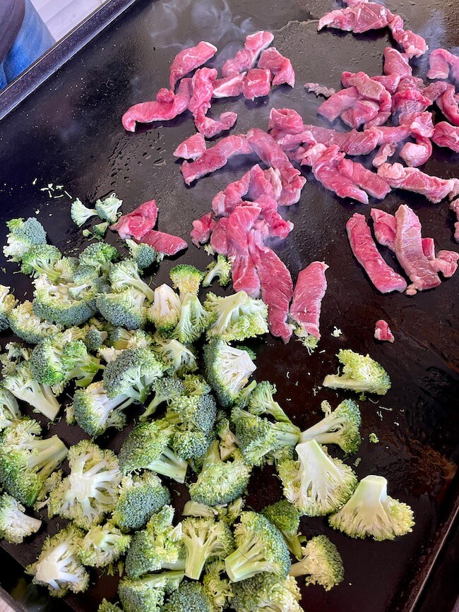 cut steak and broccoli cooking on a Blackstone griddle