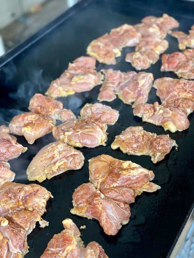 chicken thighs cooking on a griddle