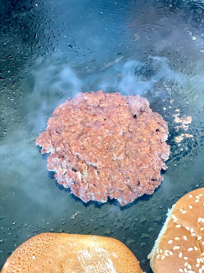 smash burger patty cooking on a griddle