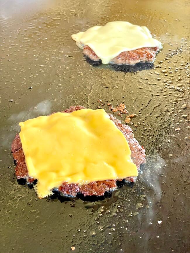 cheese smash burgers cooking on a blackstone griddle