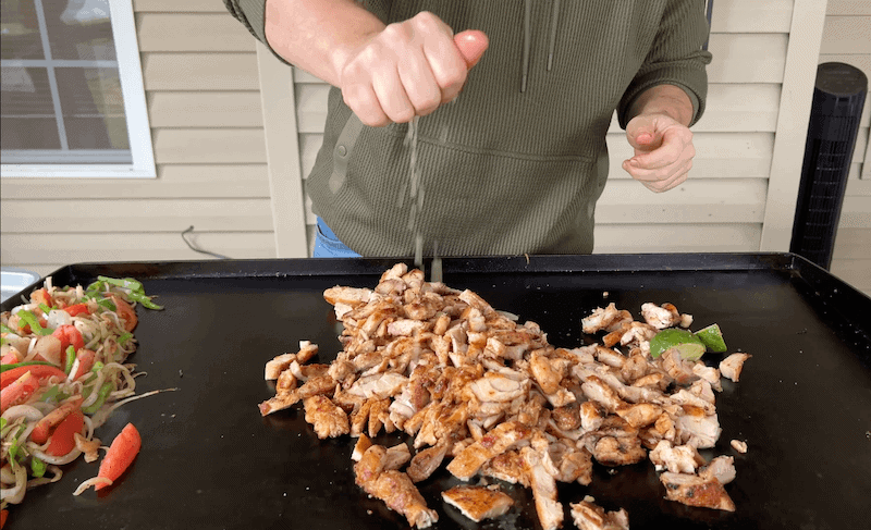 squeezing lime juice on chicken fajitas on a Blackstone griddle