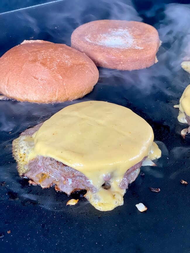 cheeseburger and buns on a griddle