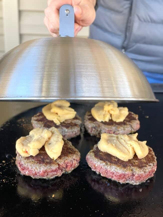 putting a melting dome over burgers on a griddle