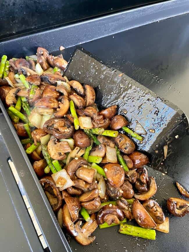 sauteeing mushrooms asparagus and onions on a griddle