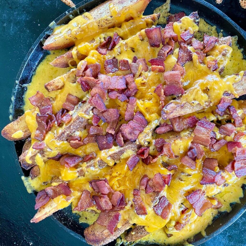 potato wedges on blackstone griddle with cheese and bacon