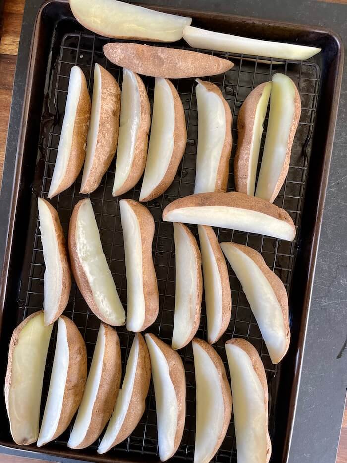 parboiled potatoes cut into wedges drying on a cooling rack