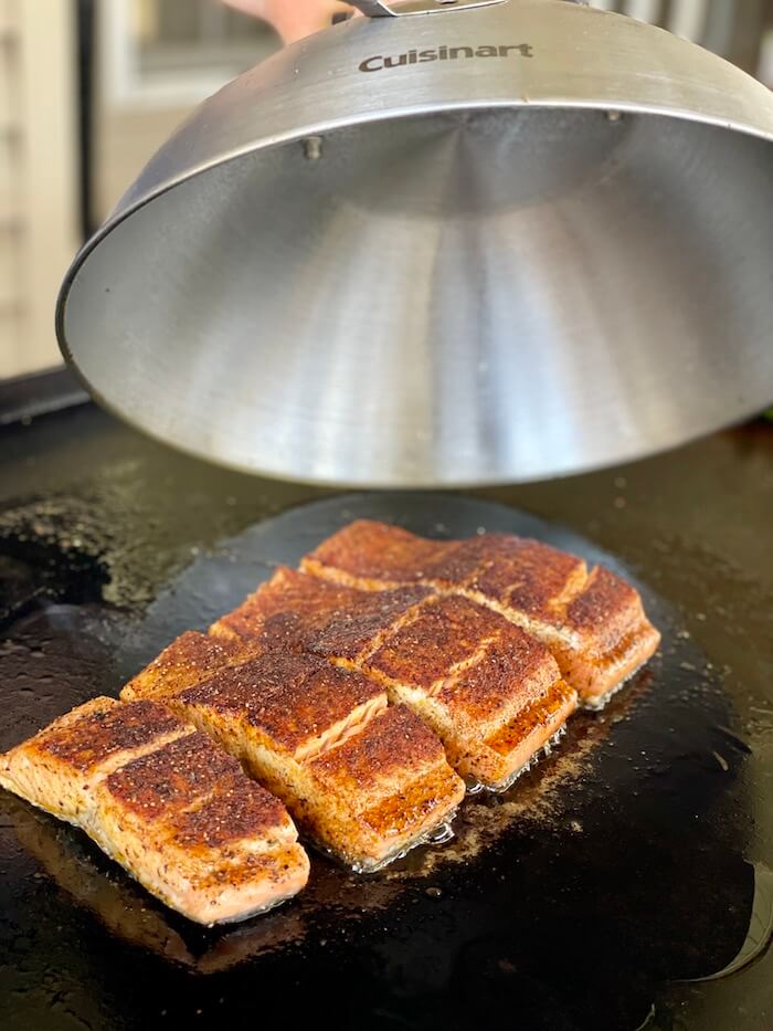 putting a dome over salmon filets on the griddle