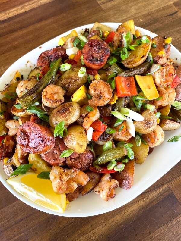 Cajun stir fry on a serving platter with lemon wedges and green onions