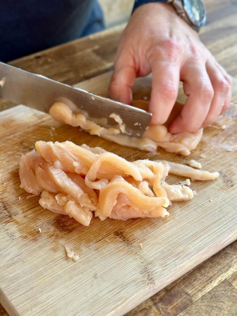 slicing chicken breast into thin strips