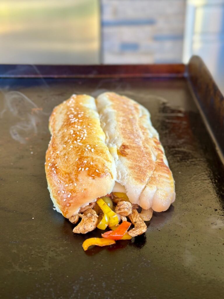 steaming a hoagie bun on top of a chicken cheesesteak mixture
