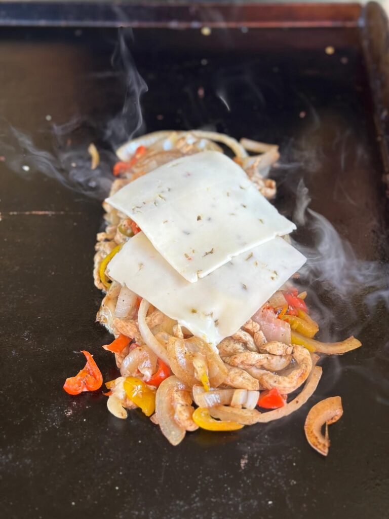 making chicken cheesesteak sandwich on the griddle
