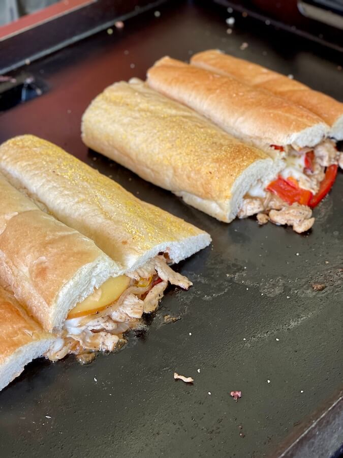 chicken philly sandwiches cooking on a griddle