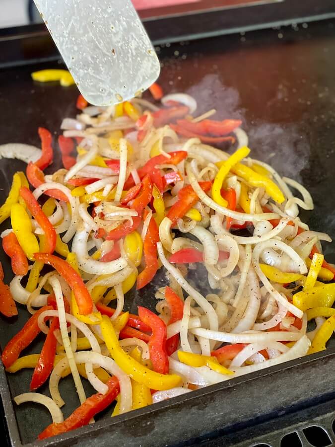 peppers and onions cooking on a griddle